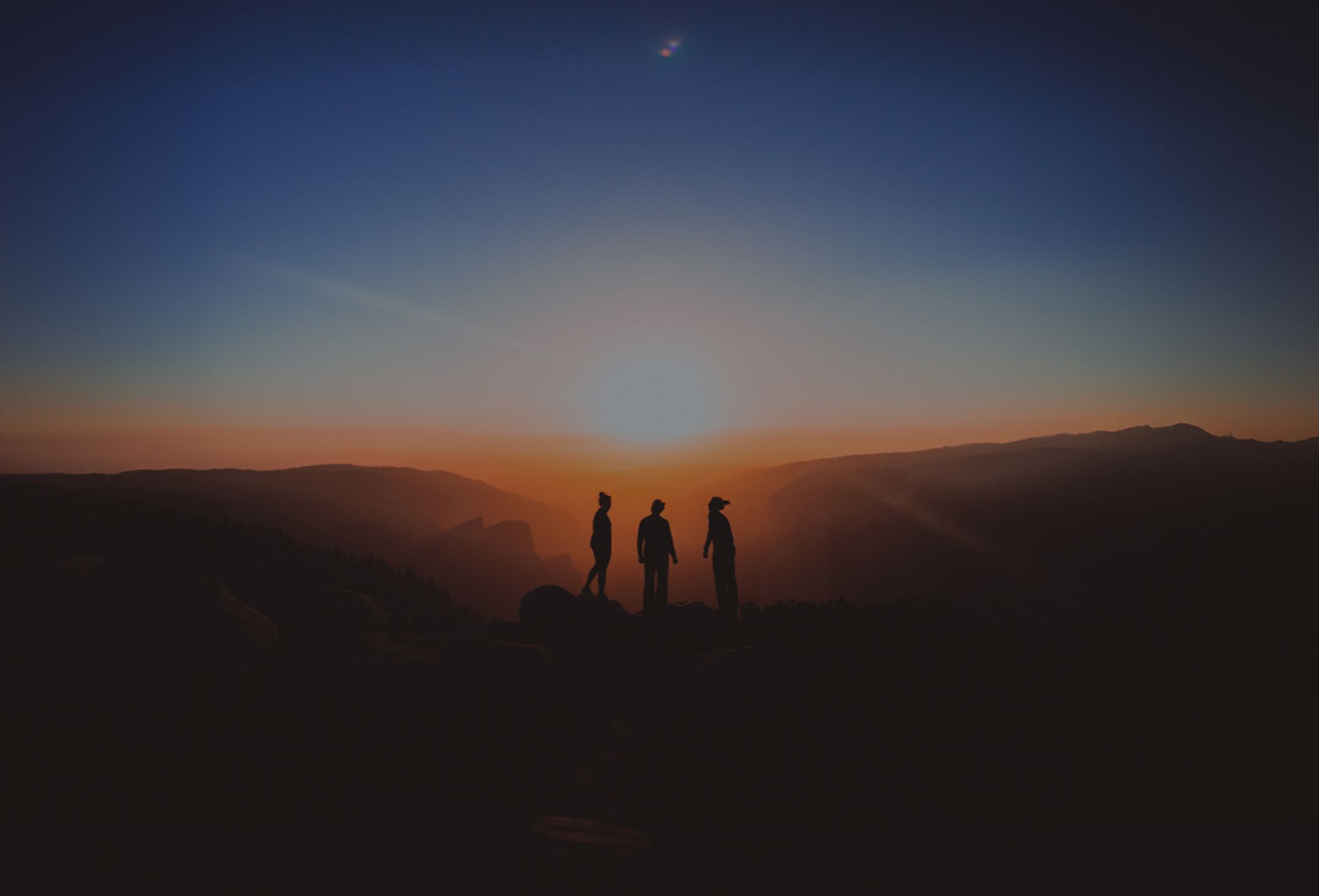 People standing in front of a sunrise